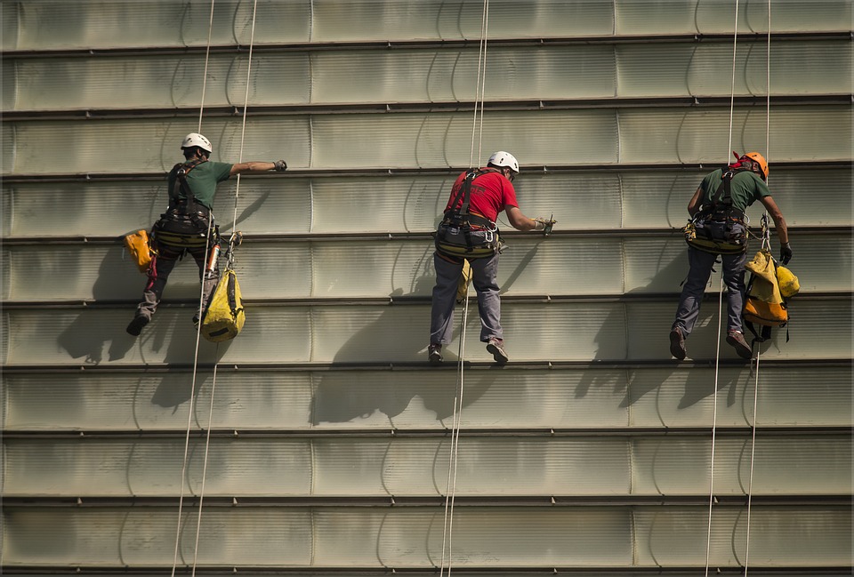 Formation travaux en hauteur Trois hommes accrochés à un harnais font du travail en hauteur